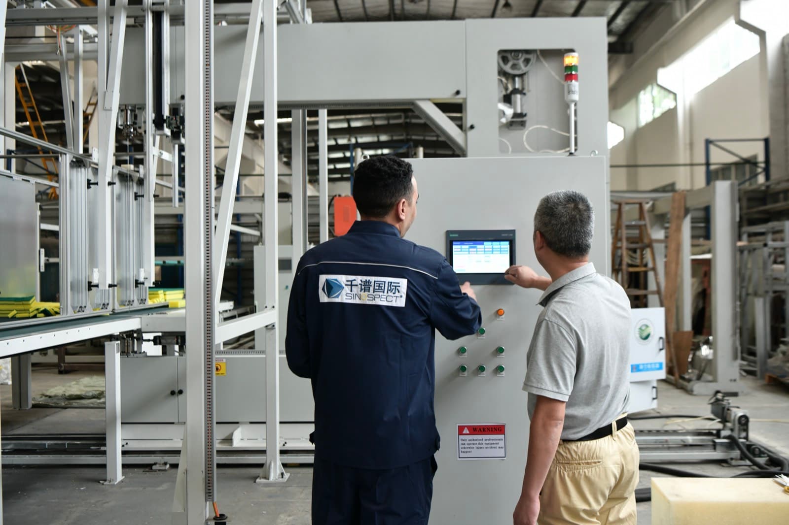 Sinospect inspector and factory engineer at a machine control panel during a factory acceptance test